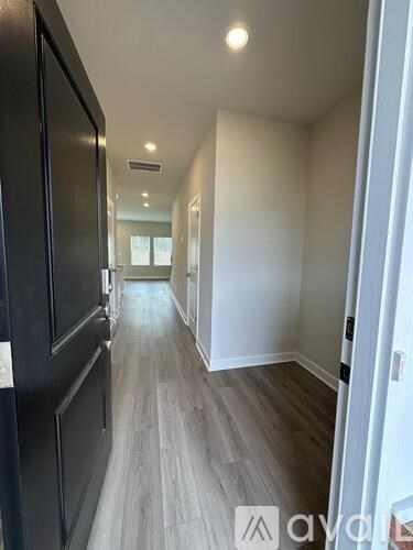A long hallway with wood floors and white walls.