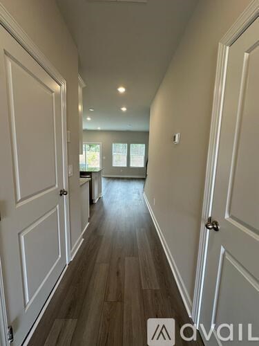 A hallway with white doors and wood flooring.