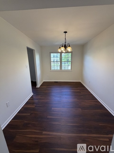 A room with wooden flooring and a chandelier.