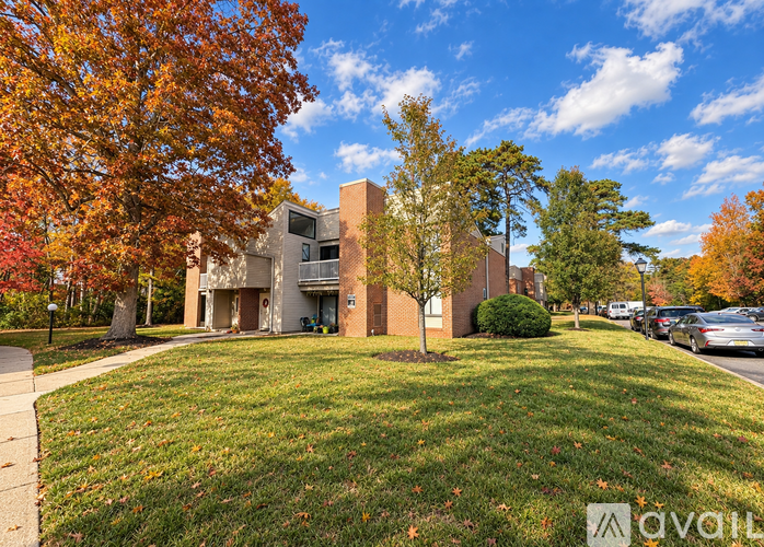 A building with a grassy area in front of it and trees with autumn leaves.