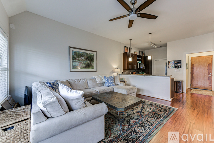 A living room with a grey couch and a ceiling fan.