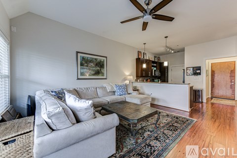 A living room with a grey couch and a ceiling fan.