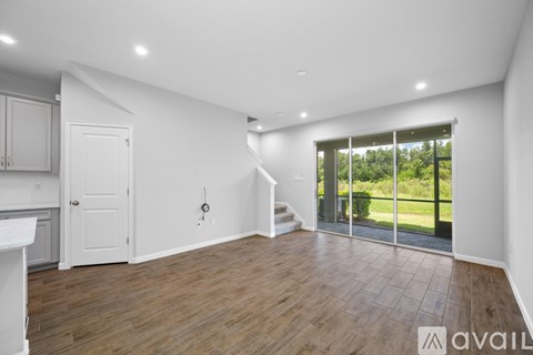 A spacious room with wooden flooring and a staircase leading to another room.