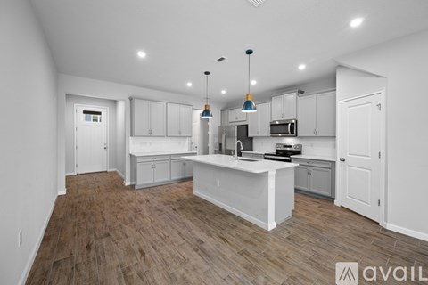 A kitchen with white cabinets and a wooden floor.