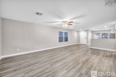 A spacious room with wooden flooring and a ceiling fan.