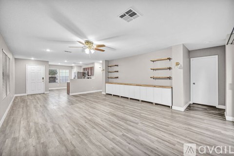 A spacious room with a ceiling fan and lighting fixture.