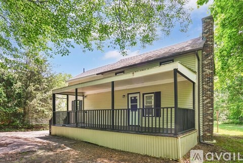 A house with a porch and a balcony is surrounded by trees.