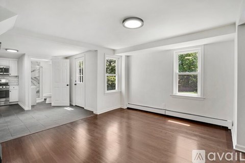 A spacious, empty room with wood flooring and white walls.