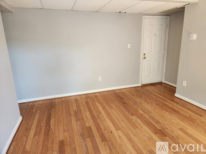 A room with wooden flooring and a white door.