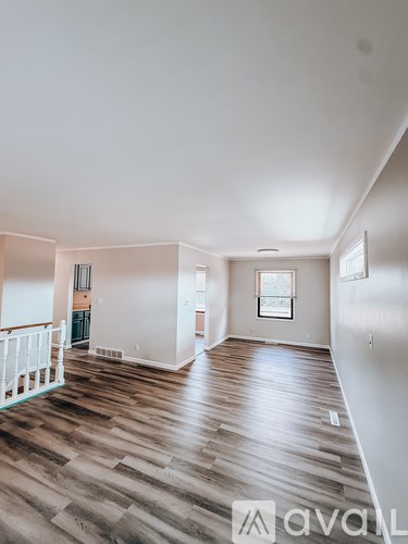 A spacious room with wooden flooring and white walls.