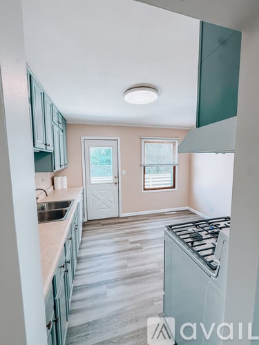 A kitchen with a stove top oven and a window with blinds.