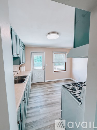 A kitchen with a stove top oven and a window with blinds.