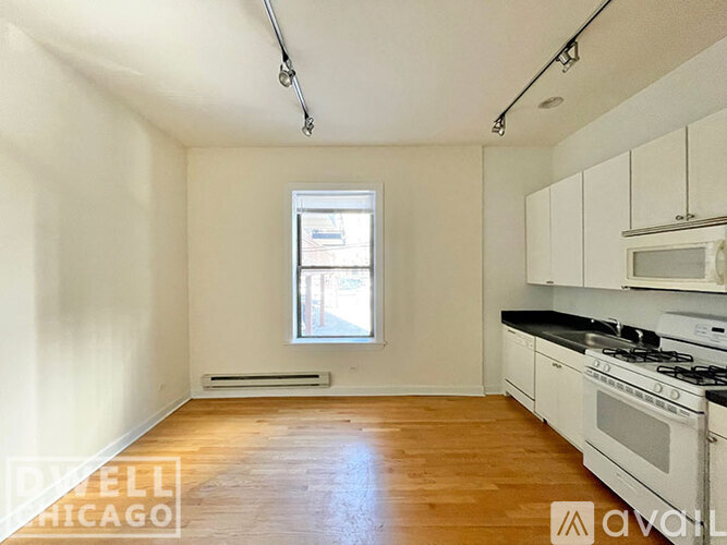 A well-lit, empty room with a window and a stove top oven.