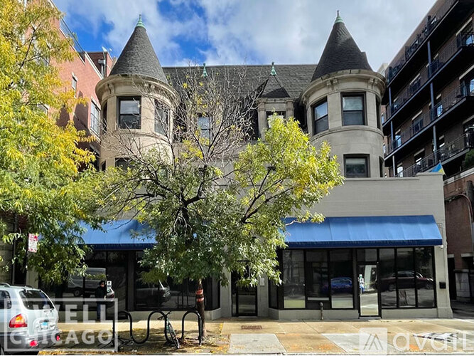 A large building with a turret is in front of a blue awning.