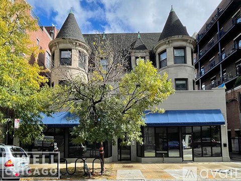 A large building with a turret is in front of a blue awning.