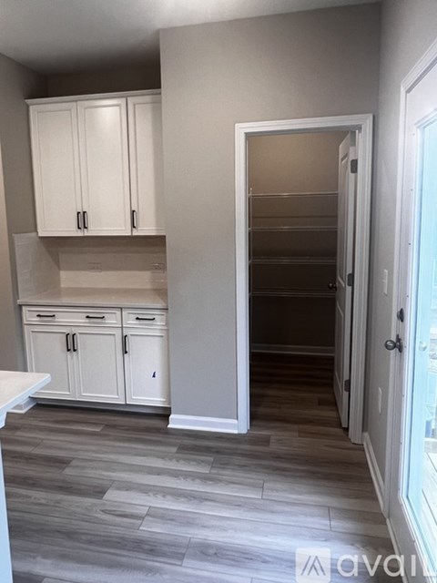 A kitchen with white cabinets and a grey floor.