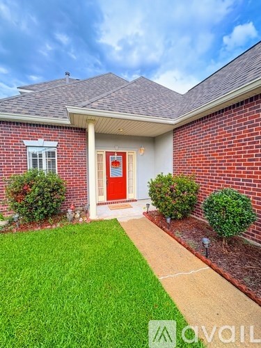 A red door is on the front of a brick house.