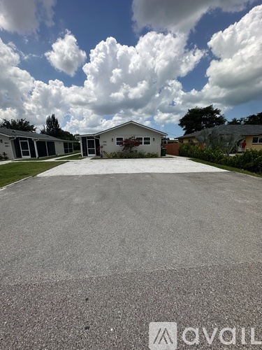 A parking lot with a building in the background and a cloudy sky.