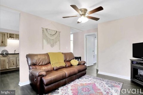 A living room with a brown leather couch and a ceiling fan.