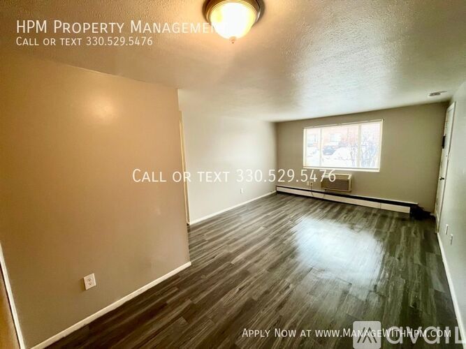 A room with wood flooring and a window, managed by HPM Property Management.