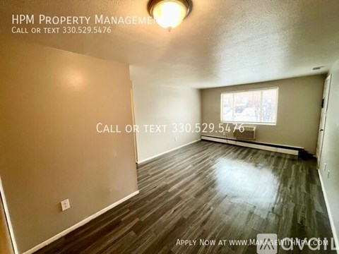 A room with wood flooring and a window, managed by HPM Property Management.