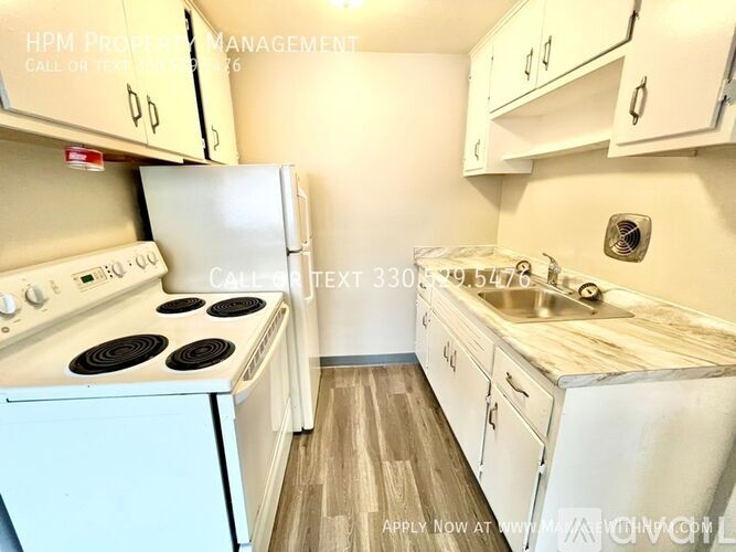 A kitchen with a white stove and cabinets.