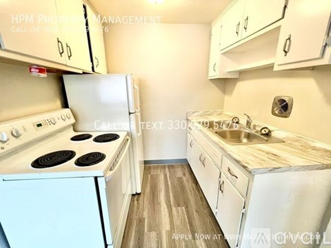 A kitchen with a white stove and cabinets.