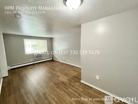 A room with wood flooring and a window with blinds.