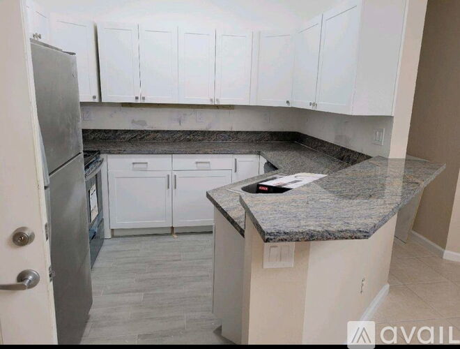 A kitchen with granite countertops and white cabinets.