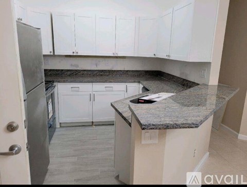 A kitchen with granite countertops and white cabinets.