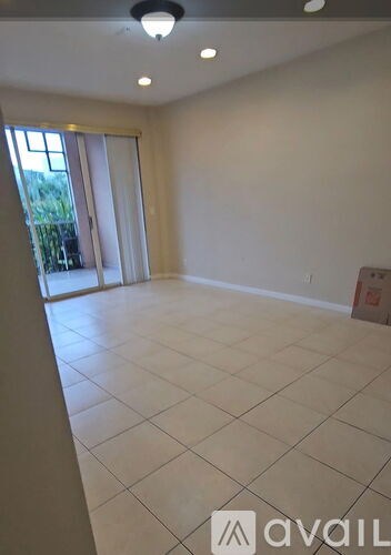 A spacious room with a tiled floor and sliding glass doors leading to a balcony.