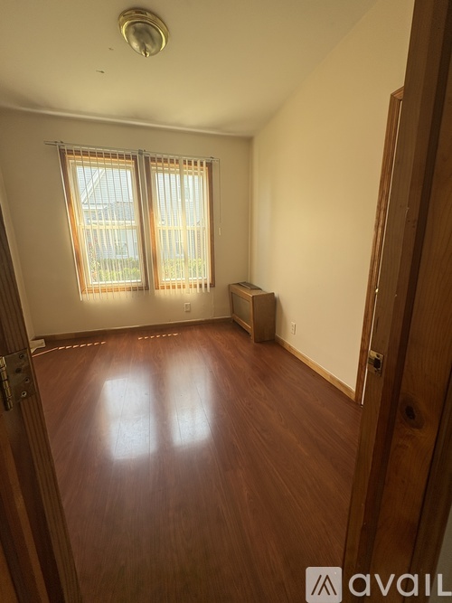A room with wooden floors and a window with blinds.