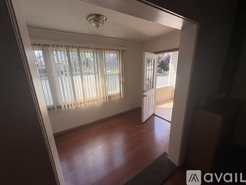 A room with wooden floors and a white door leading to a balcony.