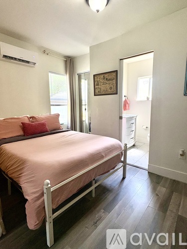A bedroom with a bed, nightstand, and a painting on the wall.