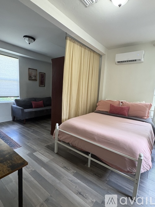 A bedroom with a pink bed and a grey sofa.