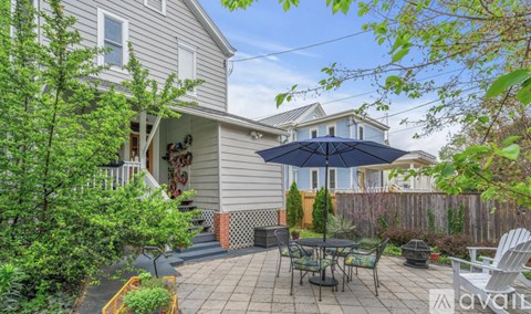 A patio with a table and chairs is surrounded by a fence and trees.