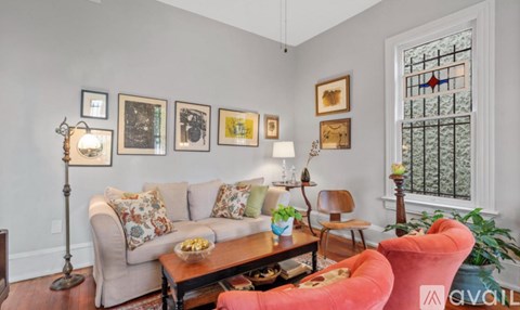 A living room with a couch, chairs, and pictures on the wall.