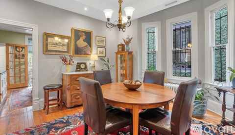 A dining room with a wooden table surrounded by chairs.