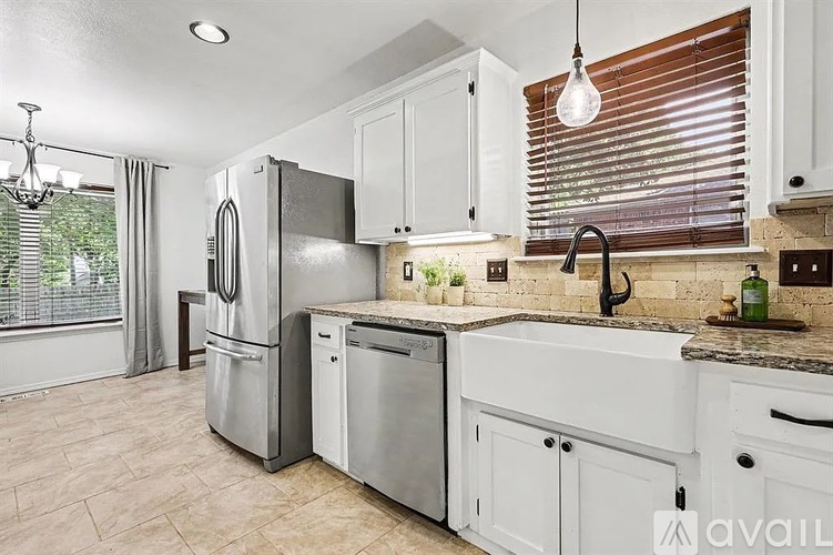 A kitchen with white cabinets and a marble countertop.