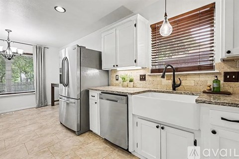 A kitchen with white cabinets and a marble countertop.