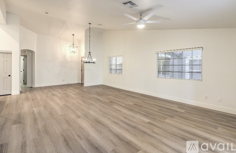 A spacious room with wooden flooring and a ceiling fan.