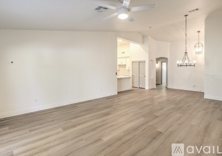 A spacious room with wooden flooring and a ceiling fan.