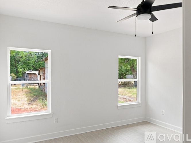 A room with two windows and a ceiling fan.