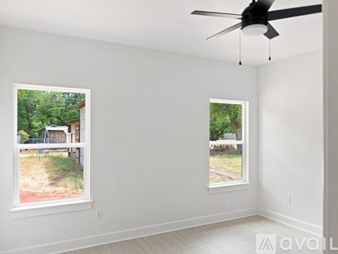 A room with two windows and a ceiling fan.