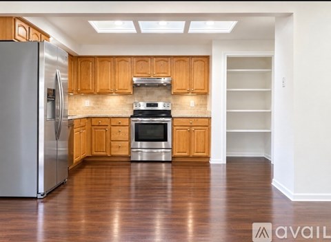 A kitchen with wooden cabinets and a stainless steel refrigerator.
