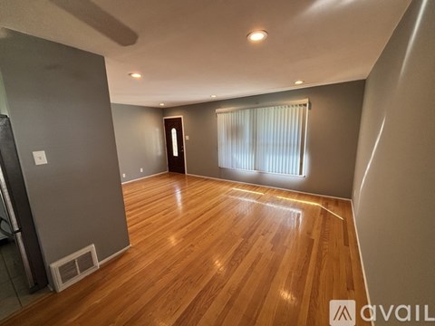 A room with wooden flooring and a window with blinds.