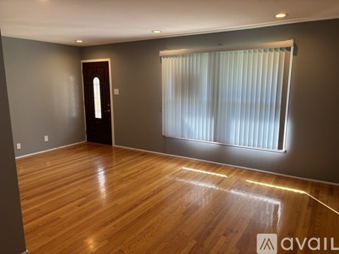 A room with wooden flooring and a window with blinds.