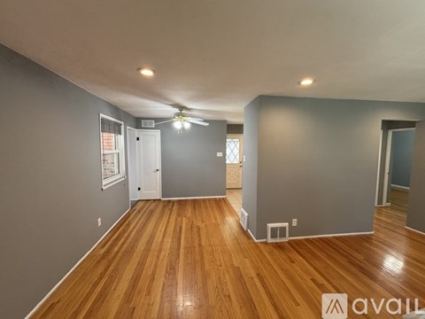 A spacious room with wooden floors and a ceiling fan.