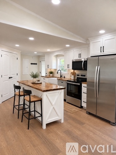 A kitchen with white cabinets and a wooden island.
