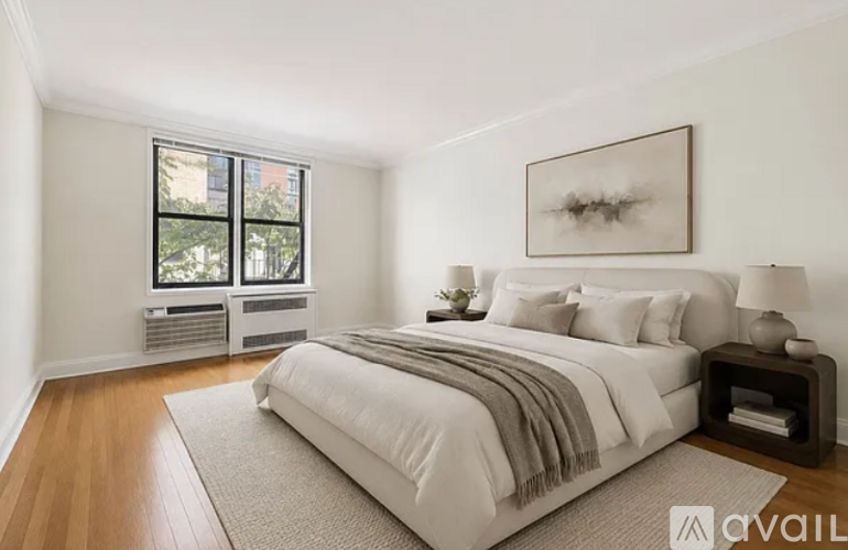 A bedroom with a large bed, a window with a view, and a framed picture on the wall.